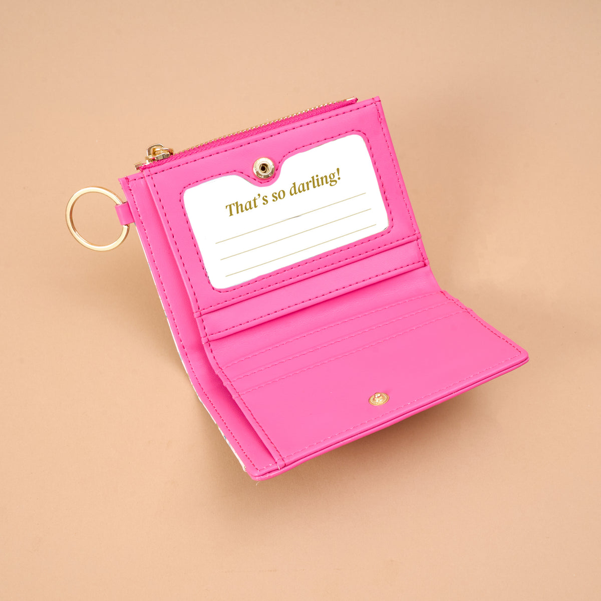 Open pink vegan leather Sugarplum Lane Luxe Pocket Wallet with a gold keyring, featuring a clear identification window printed with the text, Thats so darling!.