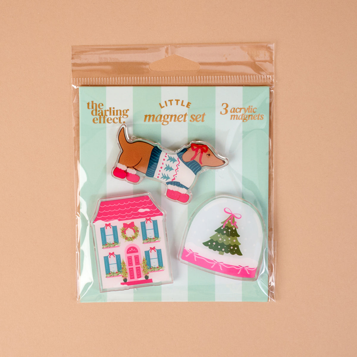 Winter Daydream Little Magnet Set featuring a dachshund in a sweater, a pink house with a wreath, and a Christmas tree inside a snow globe.