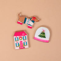 Winter Daydream Little Magnet Set featuring three decorative acrylic magnets: a dachshund in a sweater, a snow globe with a Christmas tree, and a two-story house with holiday decorations.