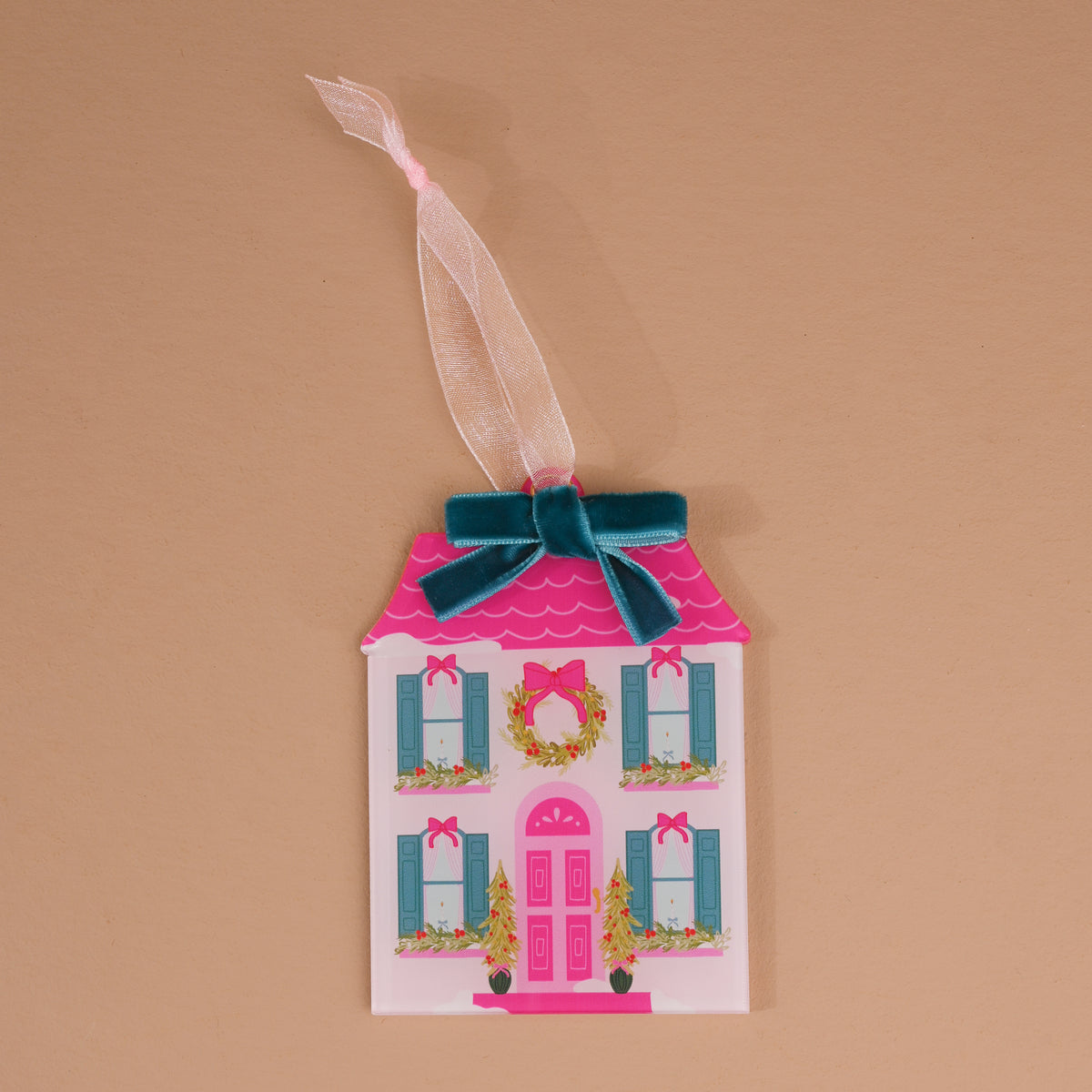 The BowBelle Manor Acrylic Ornament is a house-shaped decoration featuring a pink roof, a front wreath, a dark teal velvet bow, and a sheer ribbon loop.