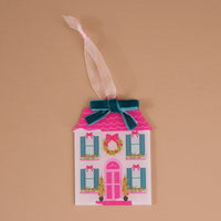 The BowBelle Manor Acrylic Ornament is a house-shaped decoration featuring a pink roof, a front wreath, a dark teal velvet bow, and a sheer ribbon loop.