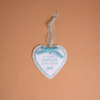 A Very Married Christmas 2026 Acrylic Ornament, featuring a heart-shaped white acrylic design with a blue scalloped border and a light blue ribbon bow.