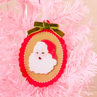 Retro Santa Acrylic Ornament, an oval acrylic piece featuring a vintage-style Santa Claus face, hanging from a pink Christmas tree with a green velvet bow at the top for elegant holiday styling.