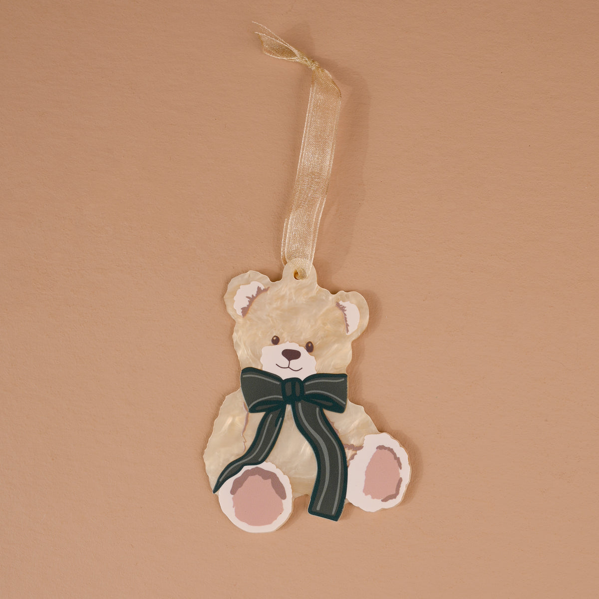Teddy Bear Theo Acrylic Ornament shaped like a teddy bear with a dark green striped bow and a ribbon hanger, perfect for holiday styling.