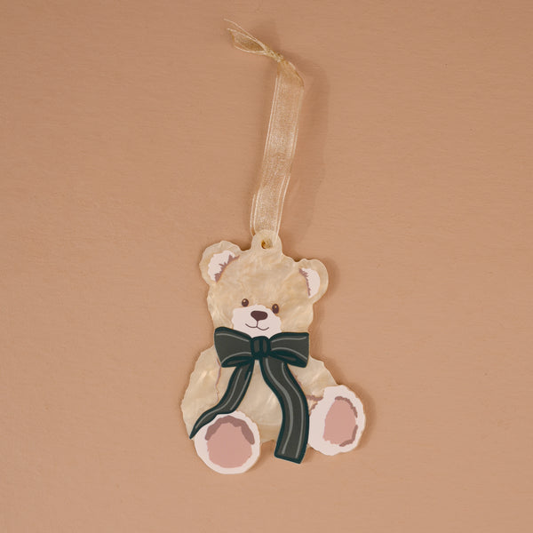 Teddy Bear Theo Acrylic Ornament shaped like a teddy bear with a dark green striped bow and a ribbon hanger, perfect for holiday styling.