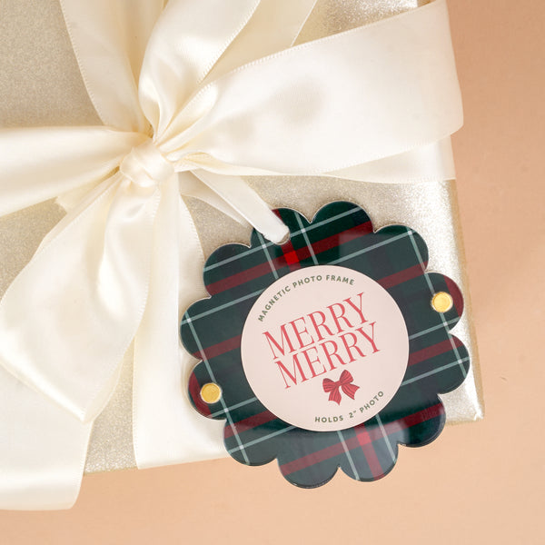 An Evergreen Plaid Scalloped Round Picture Frame Ornament in green and red plaid tied to a gift with a white satin ribbon, featuring the text Merry Merry and a red bow illustration.