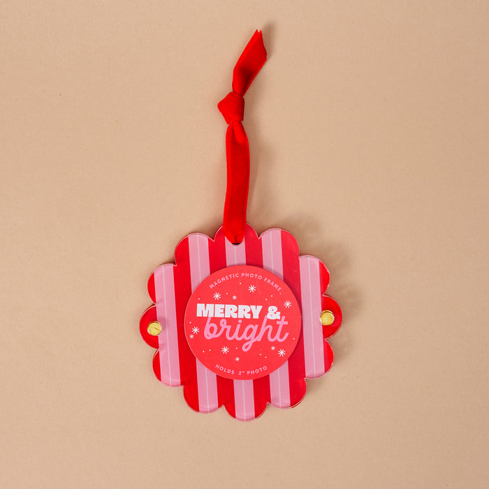 The Darling Effect's Peppermint Stripes Scalloped Round Picture Frame Ornament features red and white stripes, a red ribbon, "MERRY & bright" in white text, and snowflake accents—perfect for your holiday display!.