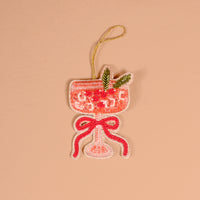 Cranberry Cosmo Handcrafted Beaded Ornament shaped like a cocktail glass filled with pink liquid, garnished with green leaves and a red bow.