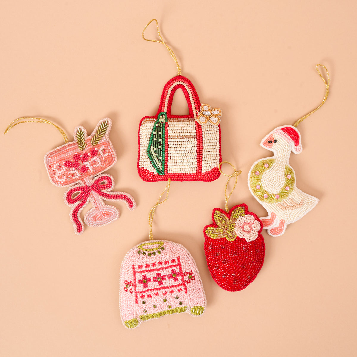 Five handcrafted beaded ornaments by The Darling Effect, including a cocktail, a tote bag, a pink sweater, a strawberry, and a Merry Silly Goose Handcrafted Beaded Ornament wearing a Santa hat.