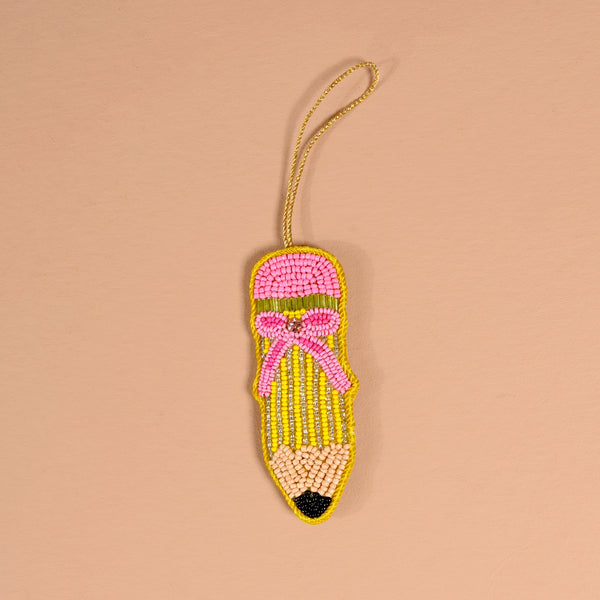 The Darling Effect Pencil Handcrafted Beaded Ornament shaped like a pencil with a pink eraser, yellow body, and black tip, featuring a decorative pink bow and a gold hanging loop.