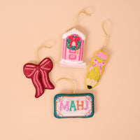 Four handcrafted beaded ornaments: a Red Bow Handcrafted Beaded Ornament, a pink door with a wreath, a yellow pencil, and a rectangular sign reading MAHJ.