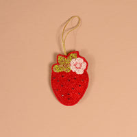 A Strawberry Handcrafted Beaded Ornament shaped like a strawberry, featuring red, green, and white beads with a gold hanging loop.