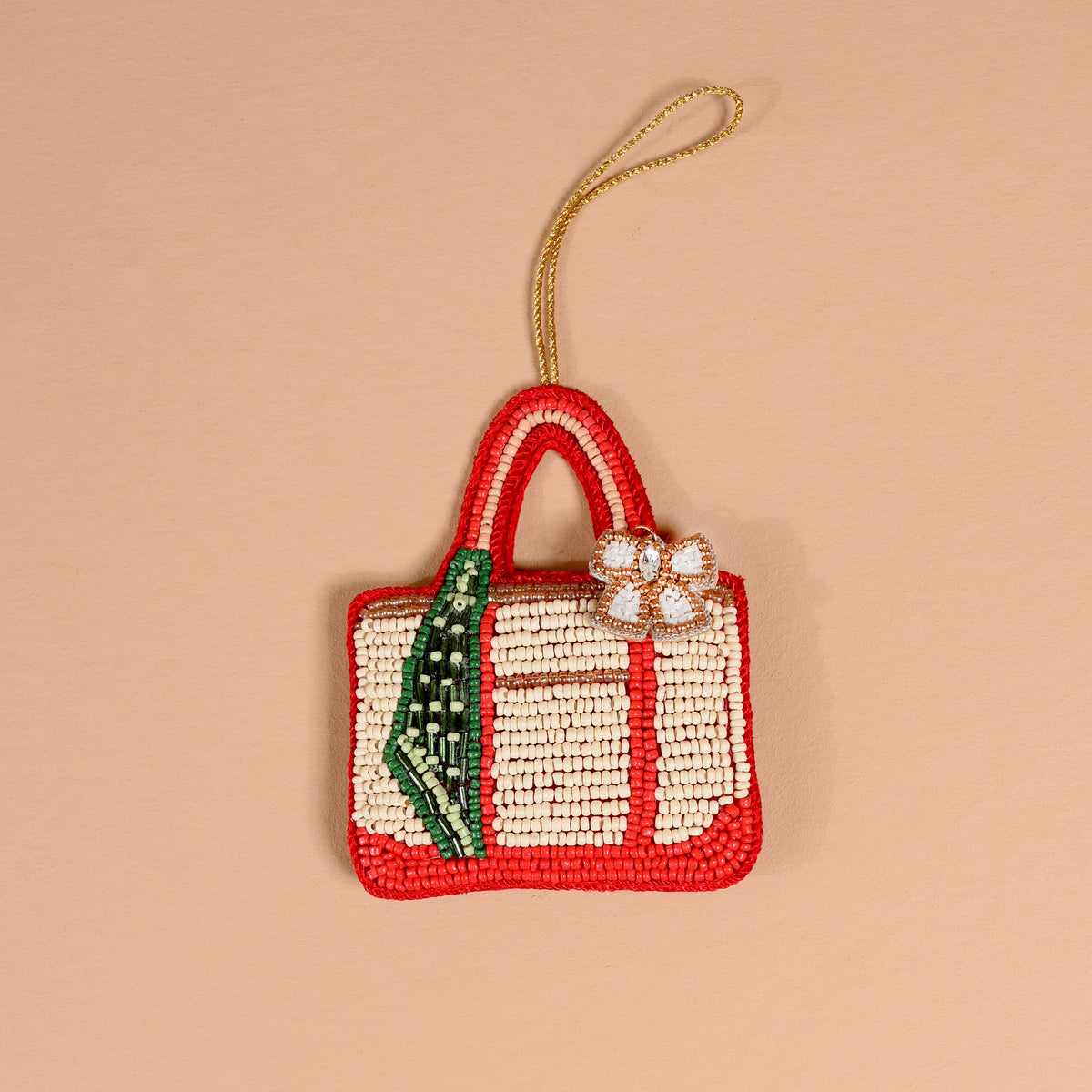 Tote of the Year Handcrafted Beaded Ornament shaped like a tote bag with red trim, a cream-colored body, a green accent, and a decorative floral charm.