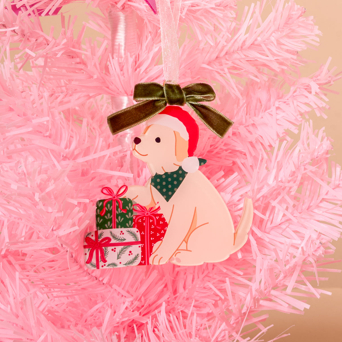 Santa Paws Acrylic Ornament featuring a light-colored puppy wearing a Santa hat and a green bandana, sitting beside a stack of Christmas presents topped with a green velvet bow.