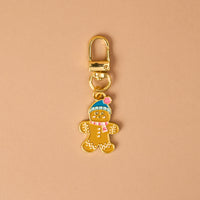 Gingerbread Pawfect Collar Charm: a gold-toned metal gingerbread person wearing a blue hat and pink scarf, attached to a lobster clasp for pet collars.