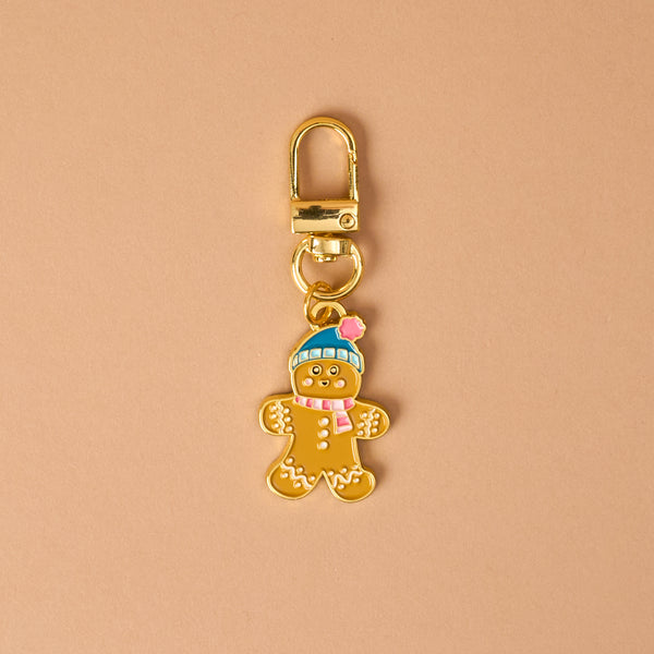 Gingerbread Pawfect Collar Charm: a gold-toned metal gingerbread person wearing a blue hat and pink scarf, attached to a lobster clasp for pet collars.