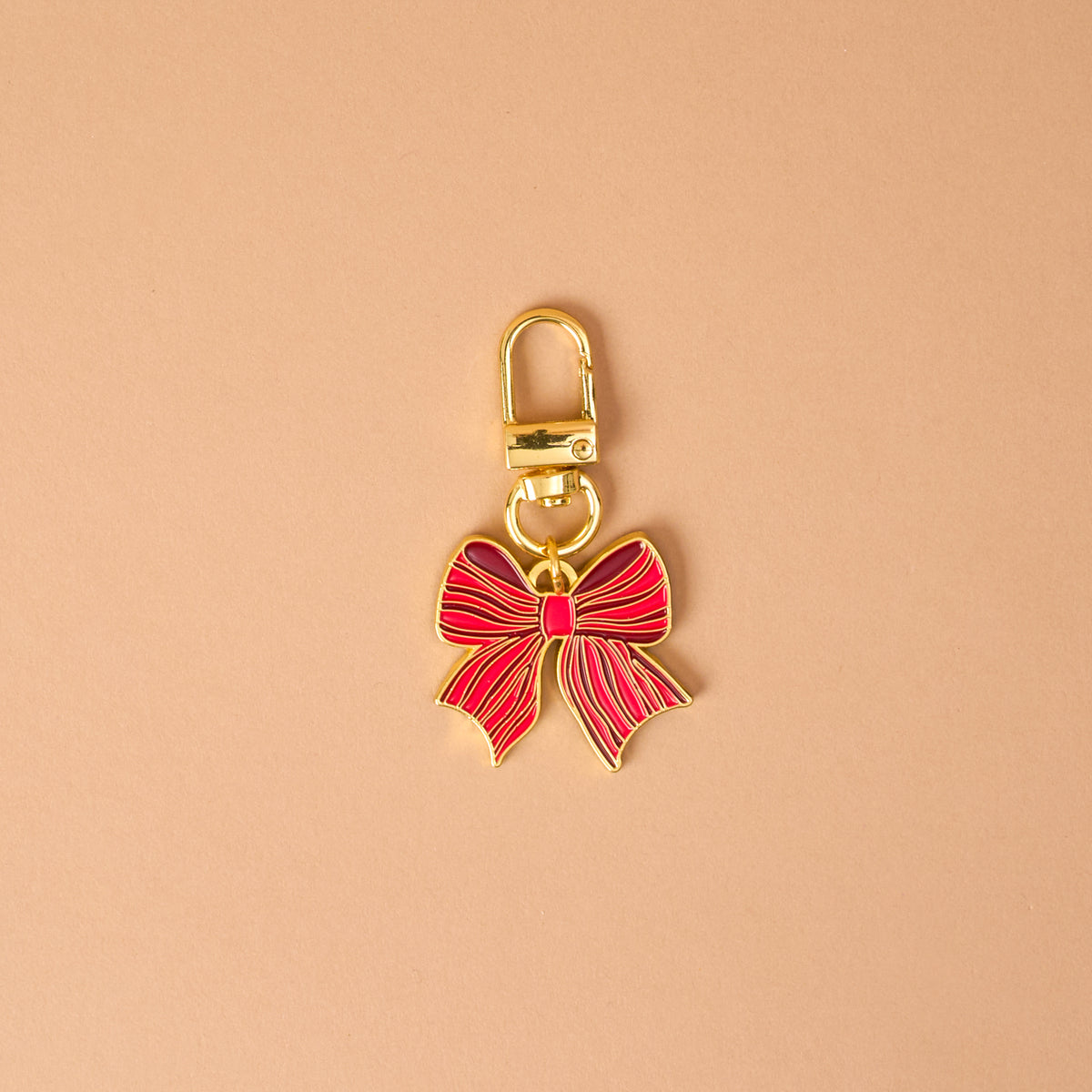 The Holiday Bow Pawfect Collar Charm by The Darling Effect is a gold-toned metal pet accessory in the shape of a red bow, featuring a lobster clasp for easy attachment to collar charms.