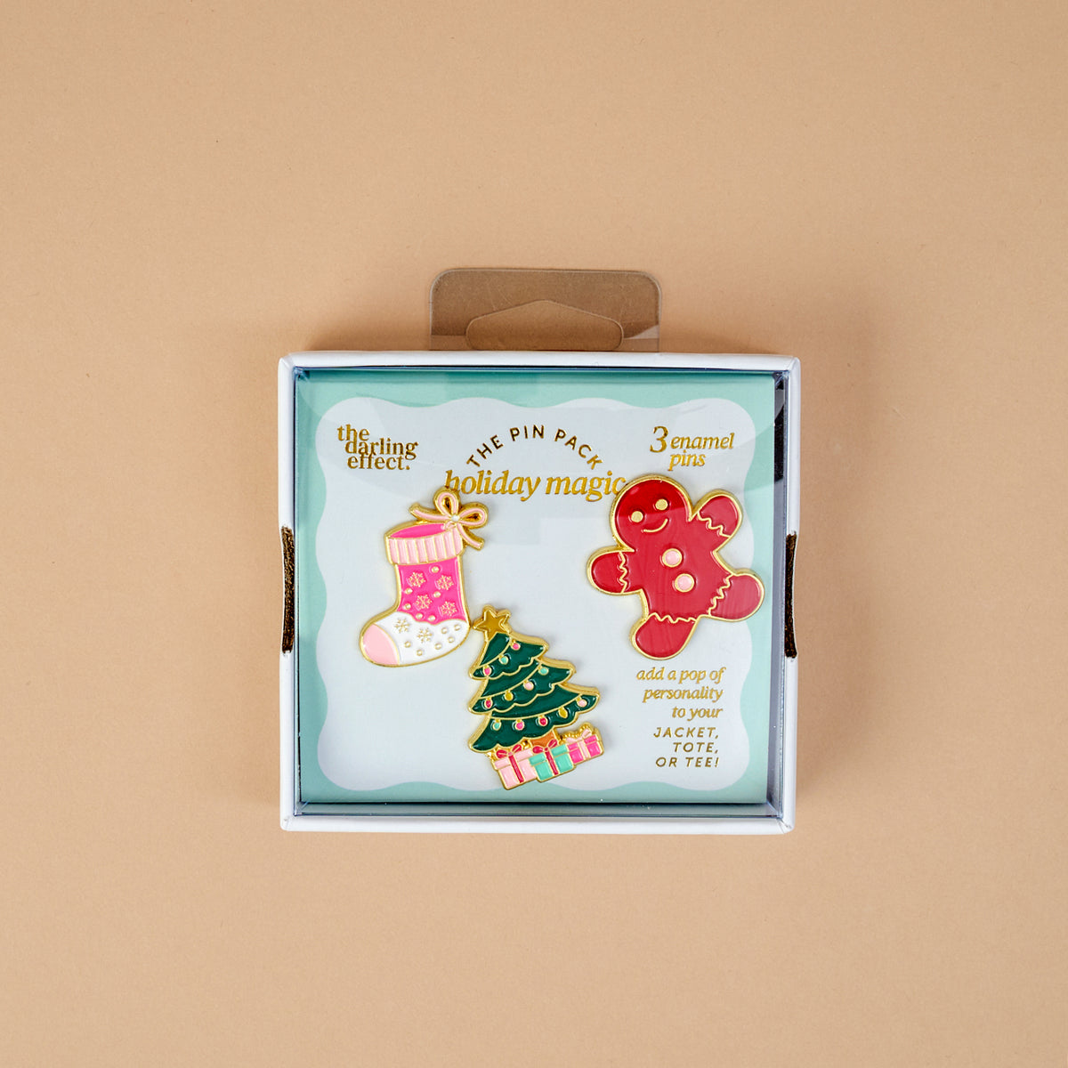 Holiday Magic The Pin Pack features three holiday-themed enamel pins: a pink stocking, a decorated Christmas tree, and a gingerbread man.