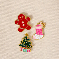 Holiday Magic The Pin Pack features a gingerbread man, a pink Christmas stocking with snowflake patterns, and a decorated Christmas tree with presents at the base.