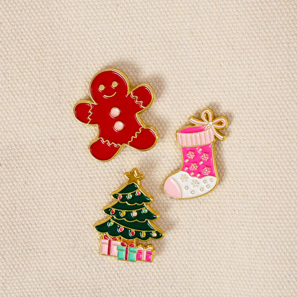 Holiday Magic The Pin Pack features a gingerbread man, a pink Christmas stocking with snowflake patterns, and a decorated Christmas tree with presents at the base.