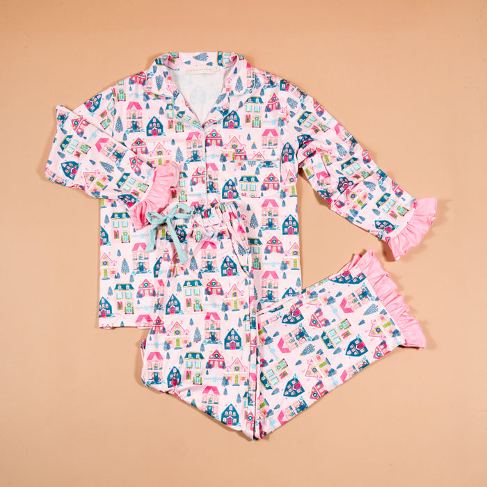 Sugarplum Lane Sweet Dreams Pajama Pants Set featuring a long-sleeved button-up shirt and matching pants with a pink Christmas village print and pink ruffled trim.