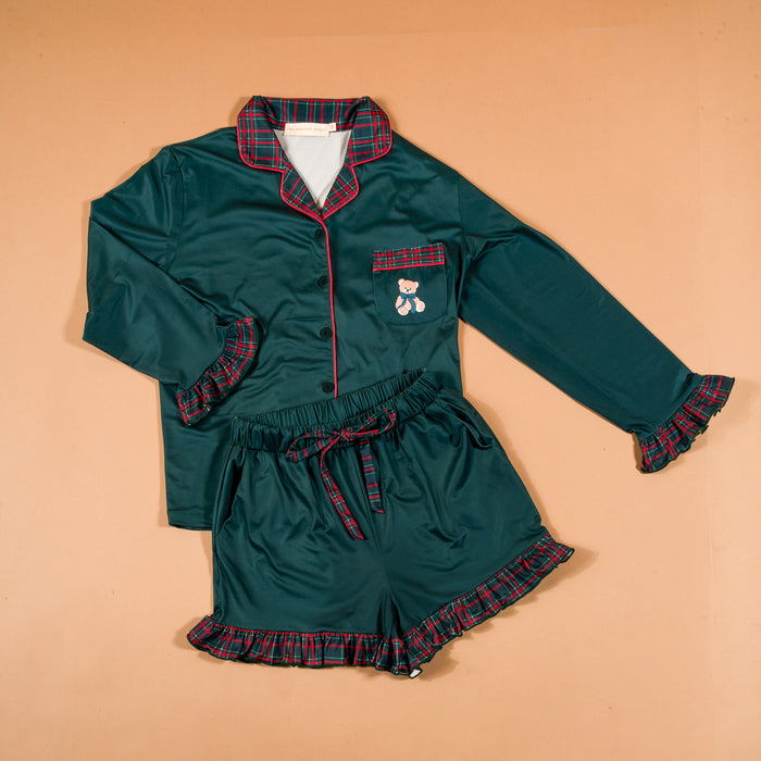 Evergreen Plaid Sweet Dreams Pajama Shorts Set in dark green featuring a button-down long-sleeve top with a teddy bear pocket, plaid trim, and matching ruffled shorts.