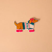 Dashing Dachshund Mix & Match Iron-On Patch featuring a dachshund wearing a tree-patterned sweater, a pink ear bow, and pink boots.