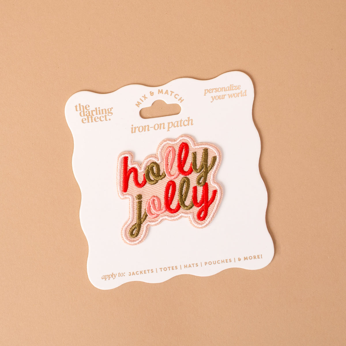 The Holly Jolly Mix & Match Iron-On Patch is an embroidered, colorful design displayed on a card, perfect for customizing your items.