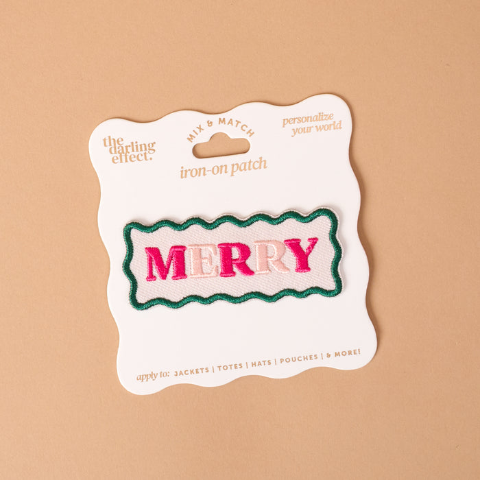 Merry Mix & Match Iron-On Patch featuring a rectangular design with a wavy green border and the word MERRY in pink letters, packaged on a branded display card.
