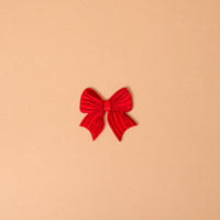 A red bow-shaped Red Bow Mix & Match Iron-On Patch used to customize jackets.