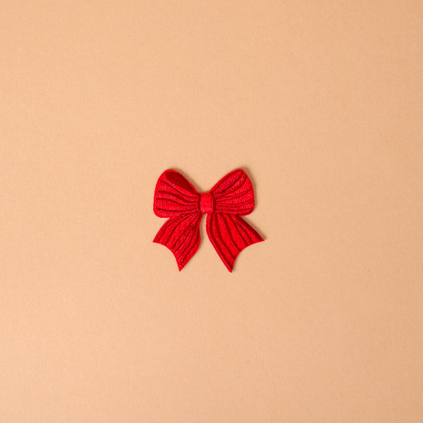 A red bow-shaped Red Bow Mix & Match Iron-On Patch used to customize jackets.
