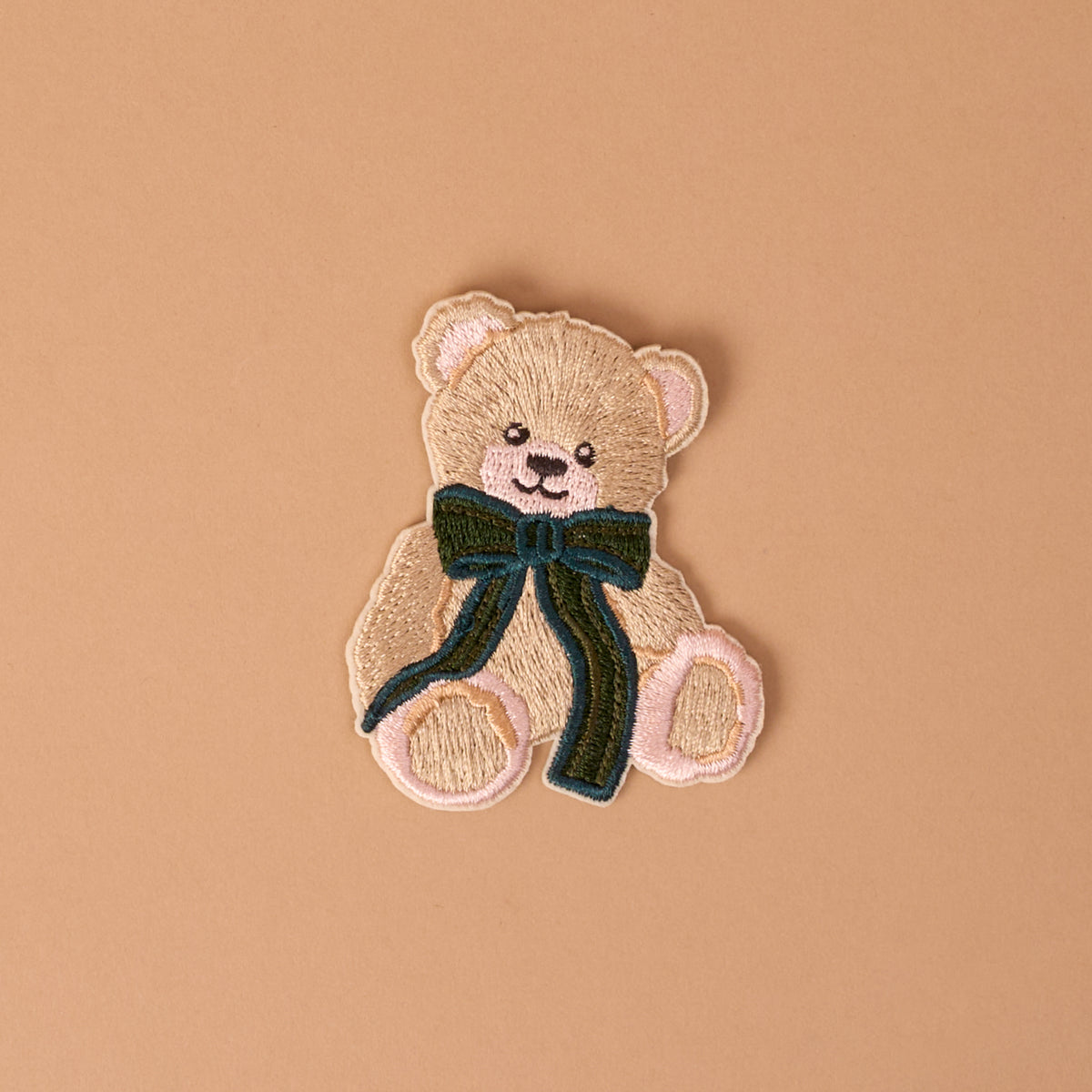 Teddy Bear Theo Mix & Match Iron-On Patch featuring a tan teddy bear with a dark green bow.