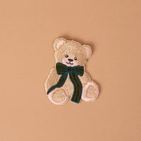 Teddy Bear Theo Mix & Match Iron-On Patch featuring a tan teddy bear with a dark green bow.