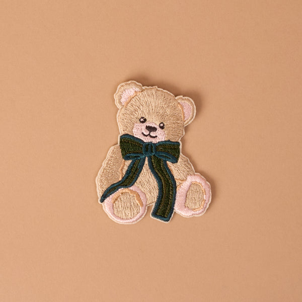 Teddy Bear Theo Mix & Match Iron-On Patch featuring a tan teddy bear with a dark green bow.