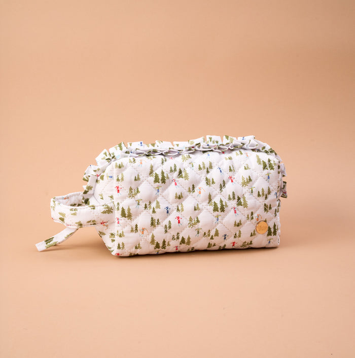 Aprés Ski Essentials Quilted Cosmetic Pouch featuring a quilted design with a ruffle trim and a pattern of skiers and evergreen trees.