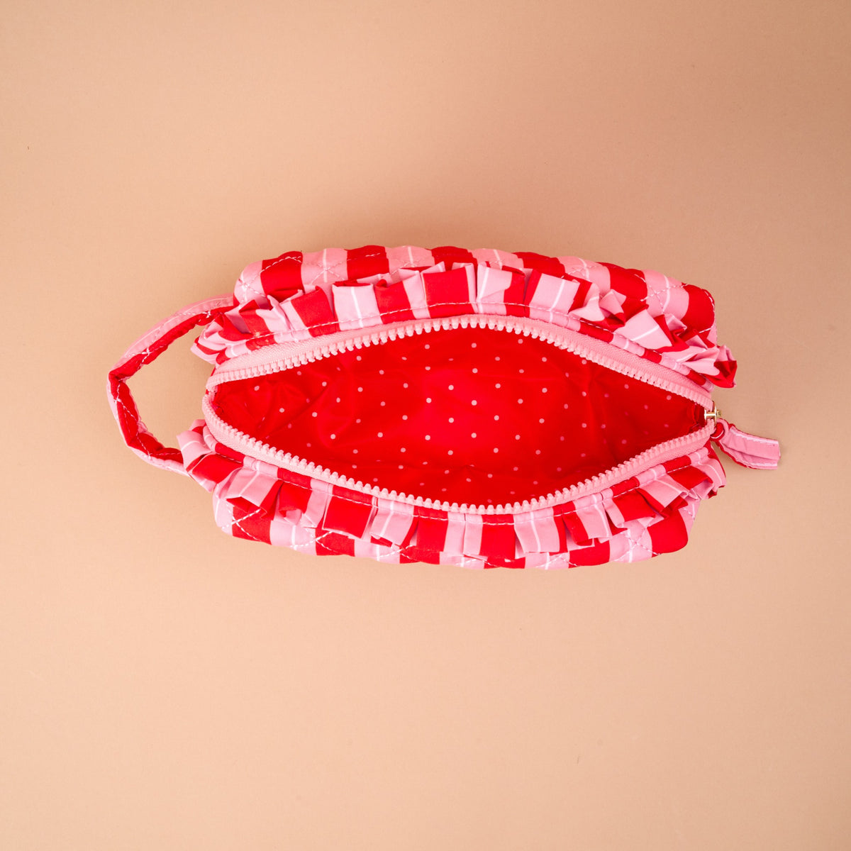 Open, quilted Peppermint Stripes Essentials Quilted Cosmetic Pouch with ruffled red and pink checkered trim and a red, polka-dotted interior.