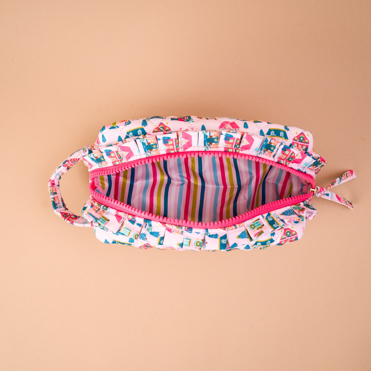 Sugarplum Lane Essentials Quilted Cosmetic Pouch in a pink house pattern, featuring a ruffled zipper trim and a multicolored striped interior.
