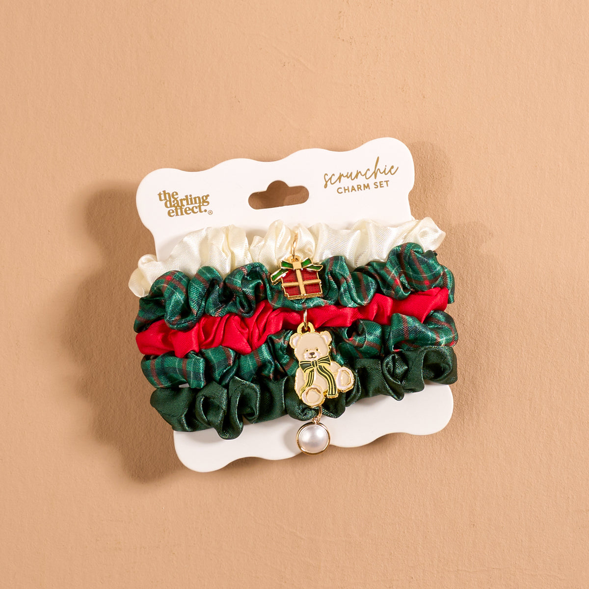Evergreen Plaid Scrunchie Charm Set featuring four stylish hair accessories in white, dark green, and red, attached to a display card with a small gift box charm and a teddy bear charm.