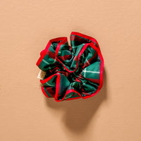 An Evergreen Plaid Ruffle Up Scrunchie featuring an oversized, ruffled design in a green, red, and white plaid pattern with a bright red edge.