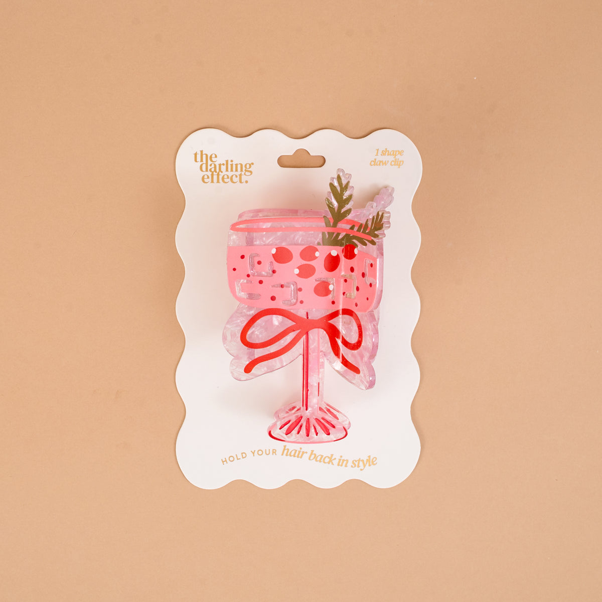 The Cranberry Cosmo Shape Up Claw Clip by The Darling Effect is a pink, cocktail-shaped hair claw clip presented on a branded card as a cute hairstyle accessory.