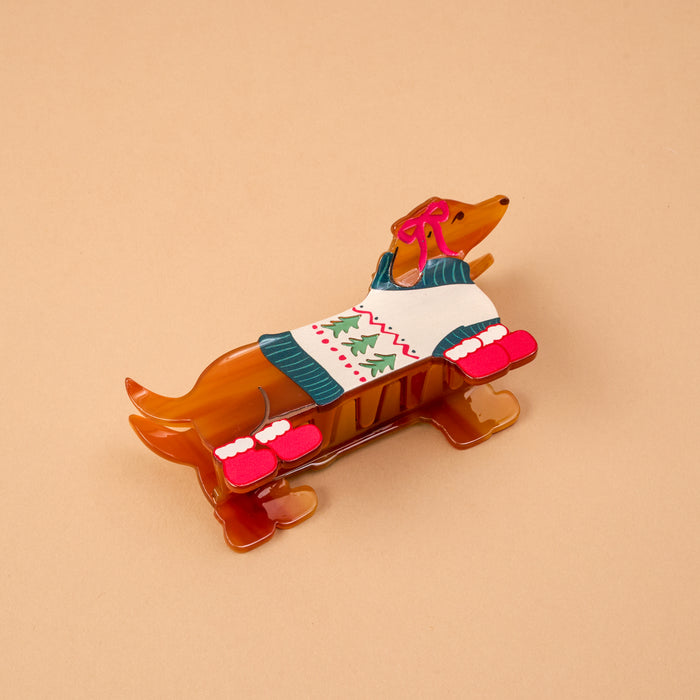 The Dashing Dachshund Shape Up Claw Clip is a brown hair clip shaped like a dachshund wearing a Christmas sweater and red mittens.