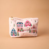 Pink Pine Village Teddy Pouch made of light pink sherpa fabric featuring embroidered colorful houses and evergreen trees.