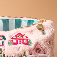 Pink Pine Village Teddy Pouch made of pink fuzzy sherpa fabric with a zipper and an embroidered winter village scene.