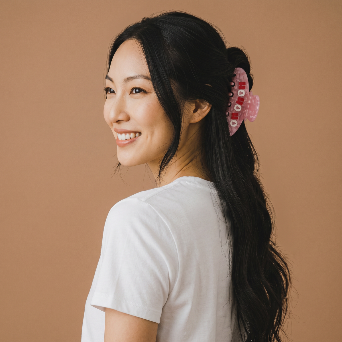 A person wearing The Darling Effect Ho Ho Ho Word Up Claw Clip, a bold, pink translucent hair clip featuring the text HO HO HO.