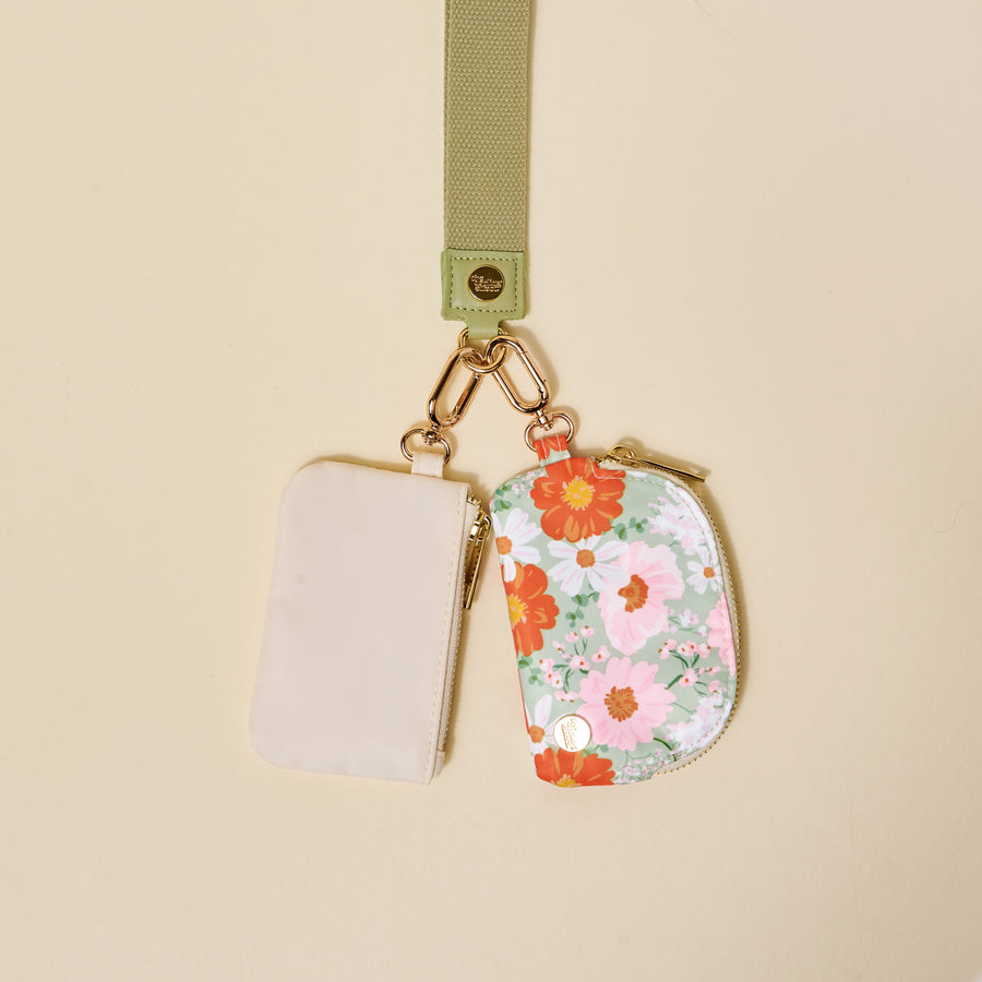 The-darling-effect’s Bouquet Beauty Sage Dynamic Duo Pouch Wristlet features a luxe lanyard with a gold clasp, holding two chic zippered pouches—one beige, one floral—for stylish hands-free carrying.