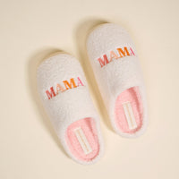 The Darling Effect's Mama Fuzzy Slippers feature soft white exteriors, pink interiors, and colorful "MAMA" embroidery on top—perfectly cozy and stylish for home comfort.