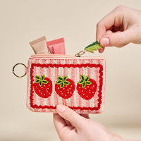 The Darling Effect's Strawberries Handcrafted Beaded Pouch features three strawberry designs and fits perfectly in two hands. Unzipped, it reveals storage space for essentials like two lip balm tubes.