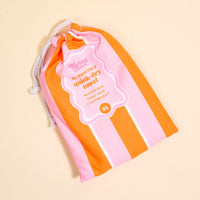 The Darling Effect Sicily Stripes Pink XL Quick-Dry Beach Towel comes in a pink and orange striped drawstring bag. It's sand resistant, lightweight, and extra-large—perfect for all your beach adventures!.