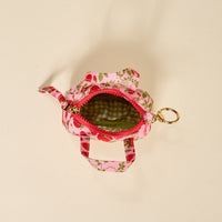 The Darling Effect’s Strawberry Fields Itty Bitty Duffle Bag Charm is a small, floral-patterned fabric bag with two handles, a top zipper, and green checkered lining—an ideal accessory—shown from above on a light surface.