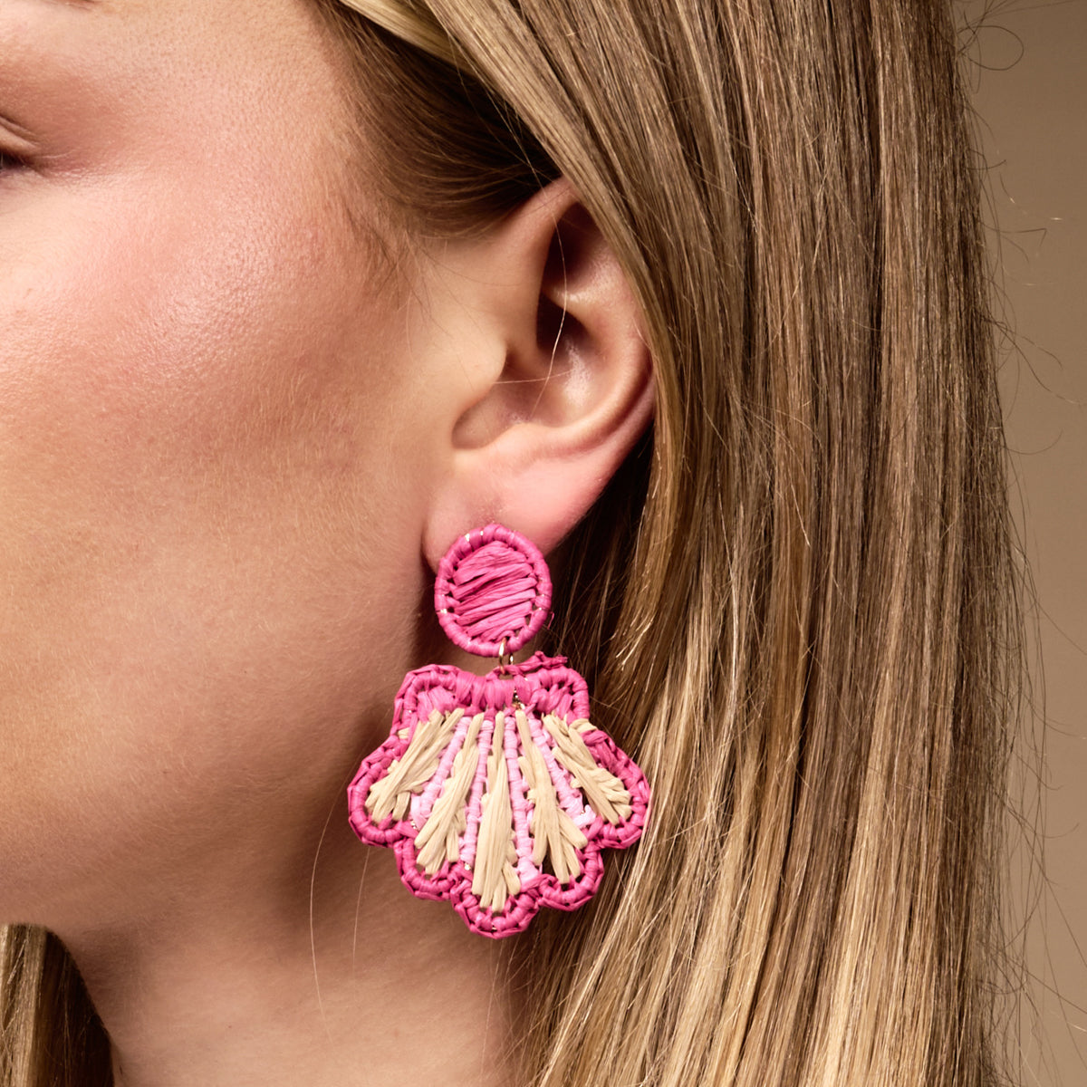 Close-up of a woman's ear wearing The Darling Effect's Hot Pink Cabana Breeze Earrings with shell design, partially hidden by long blonde hair—stylish and perfect for everyday wear.